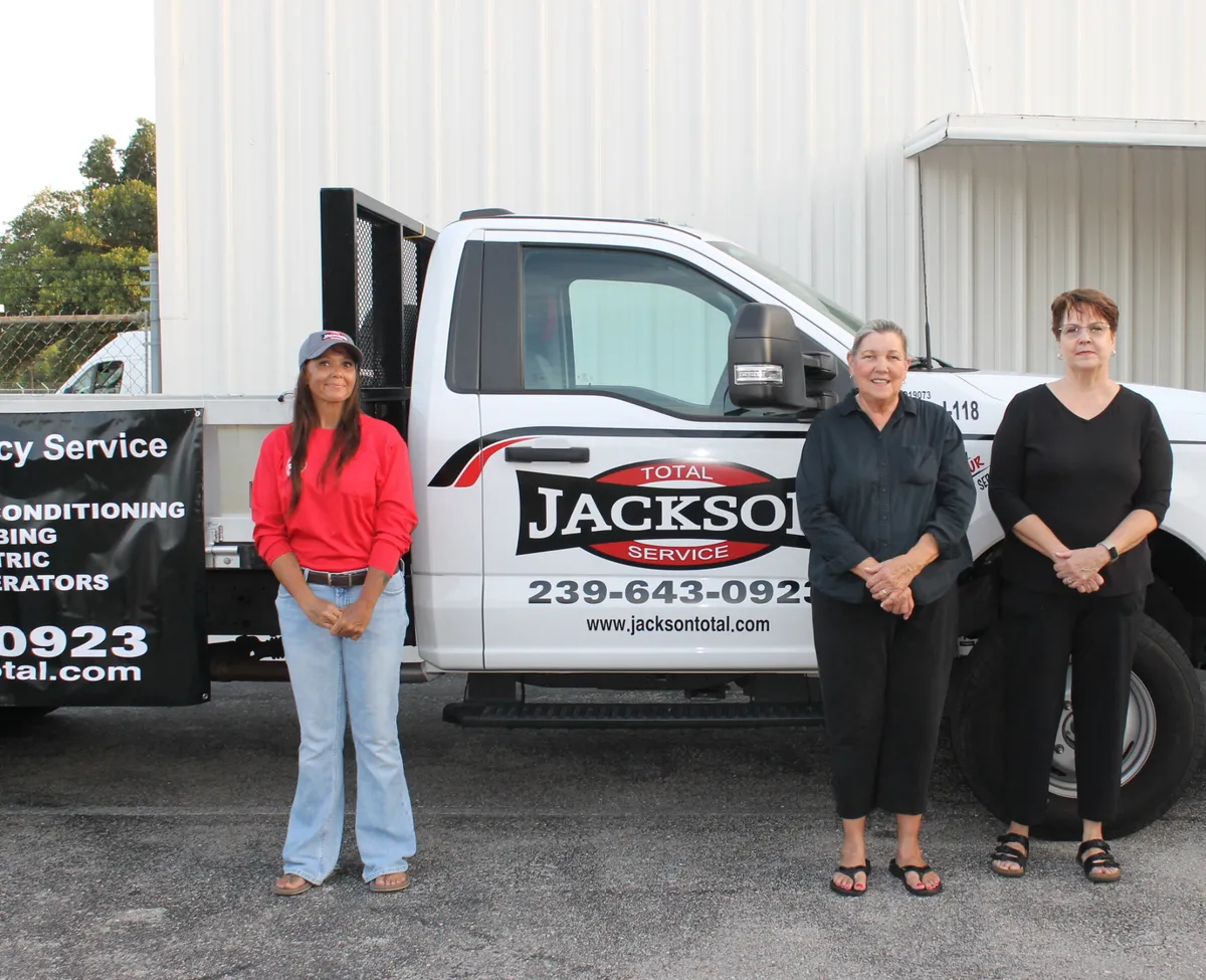 Jackson Total Service office team members beside a lettered company truck